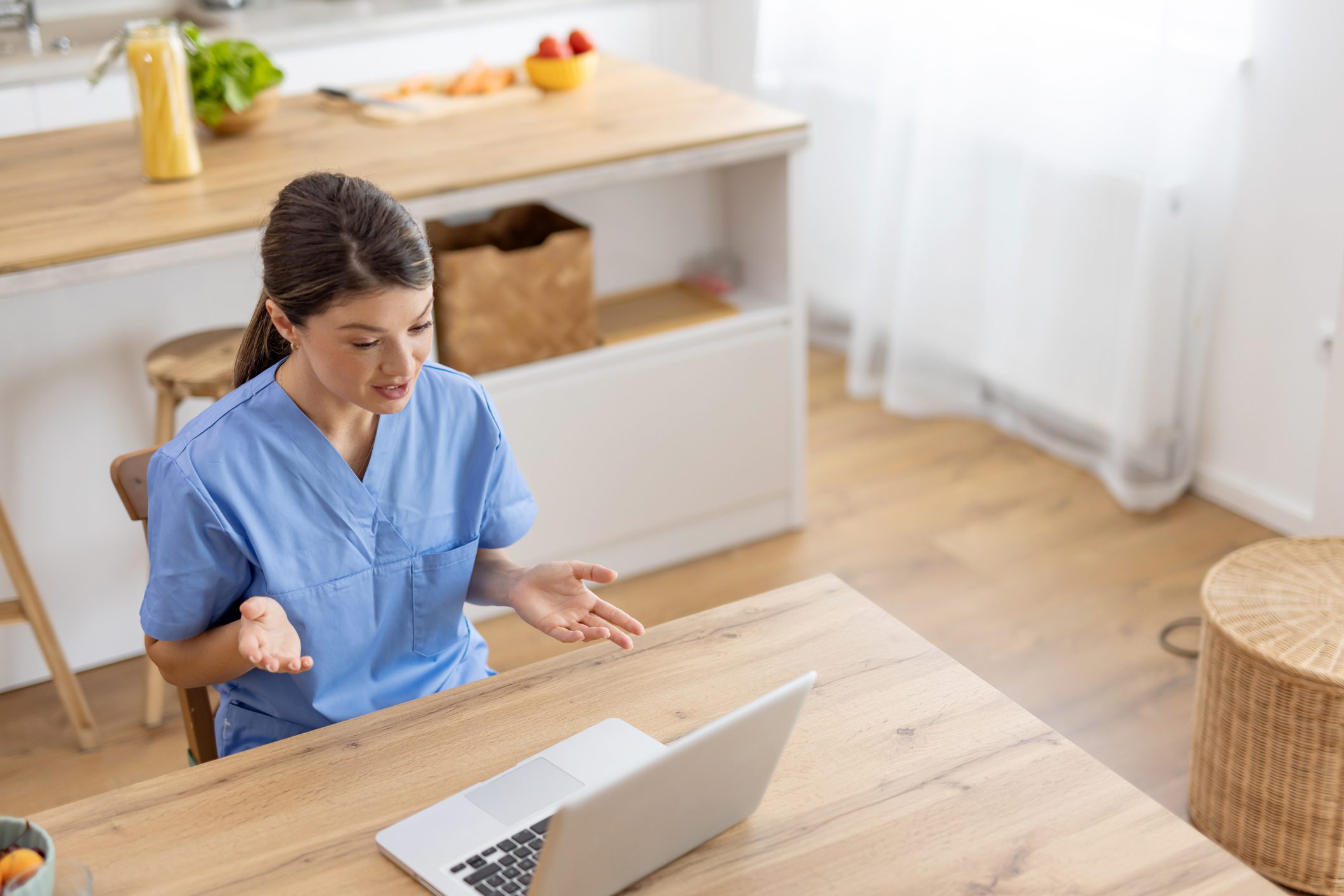 Person in scrubs video calling on laptop.