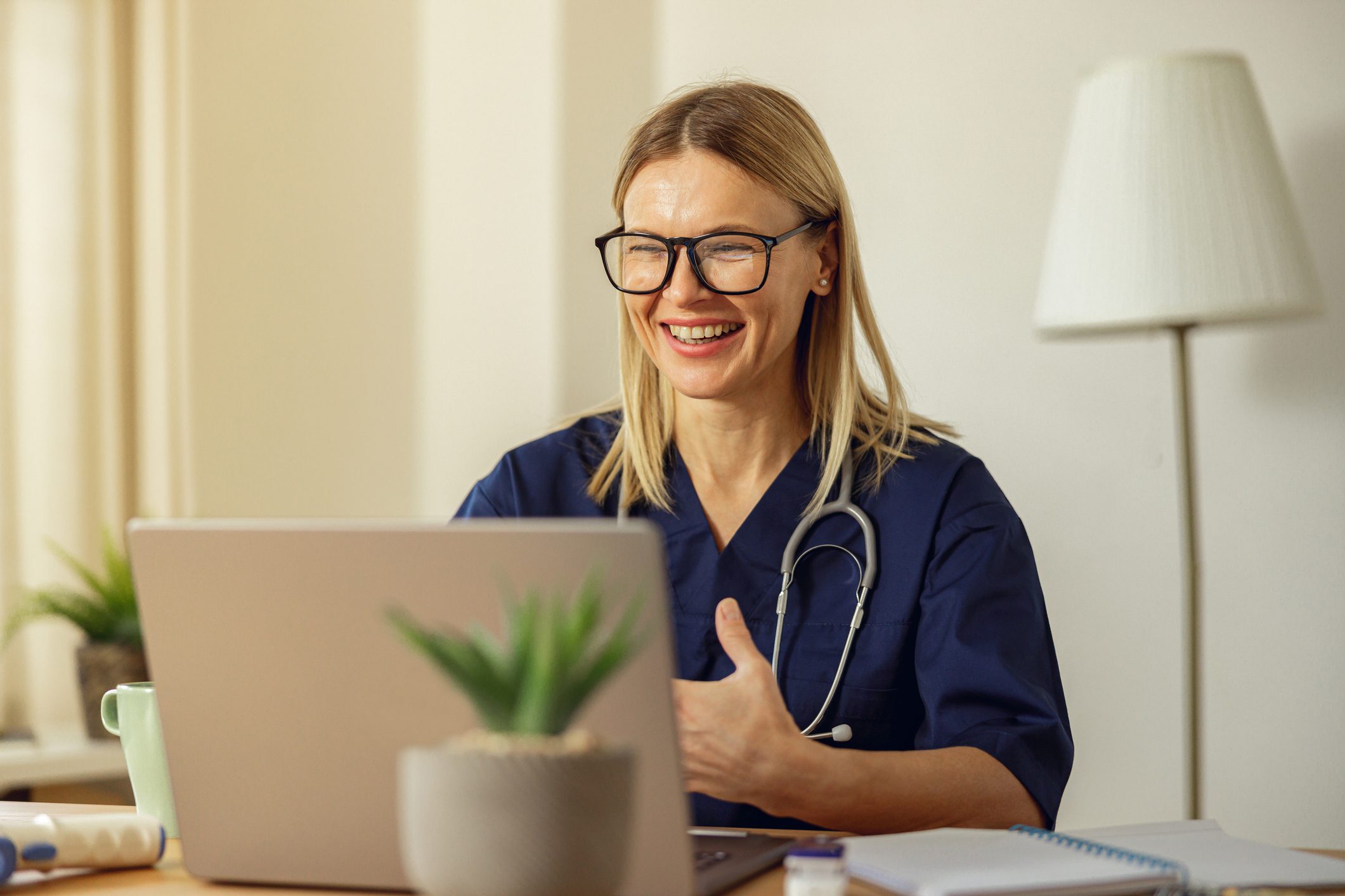 Smiling female doctor video chatting on laptop.